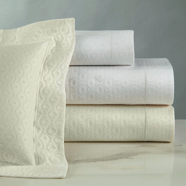 Home Treasures Mirage ivory and white cotton sheets with embossed circle pattern, folded and stacked.