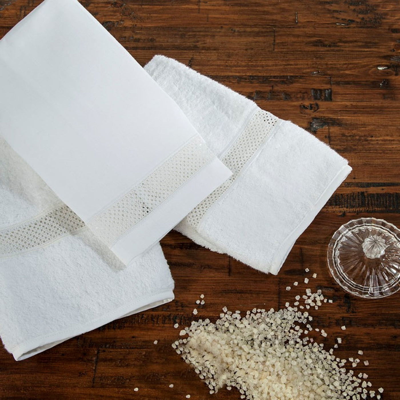 Sferra Morocco white bath towels with mesh border on dark wood surface.