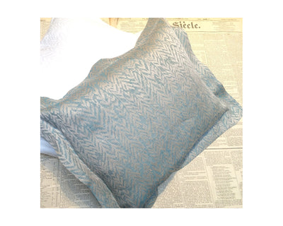 A light blue patterned pillowcase with a subtle zigzag design rests on sheets of vintage newspaper.