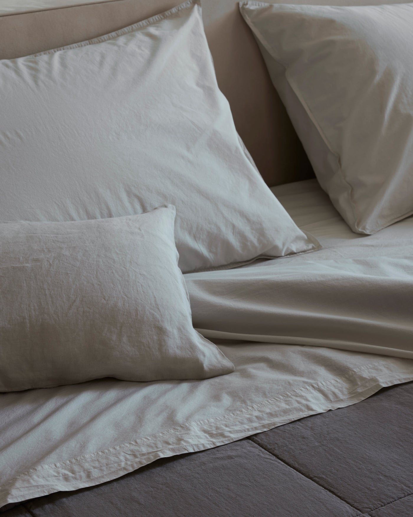 Nite cotton pillowcases and flat sheet in ivory on a styled bed.