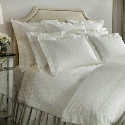 Sferra Plush 1000 Stripe ivory cotton bedding collection styled on a bed.