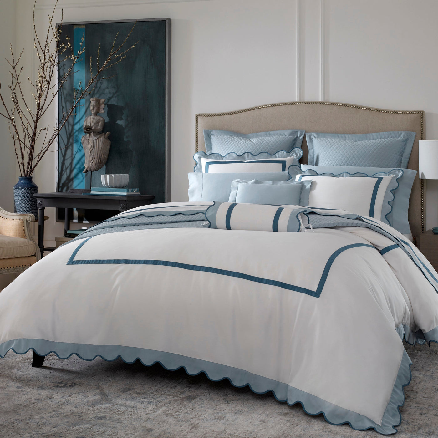 Sferra Portofino white and teal blue scalloped edge bedding collection on styled bed.