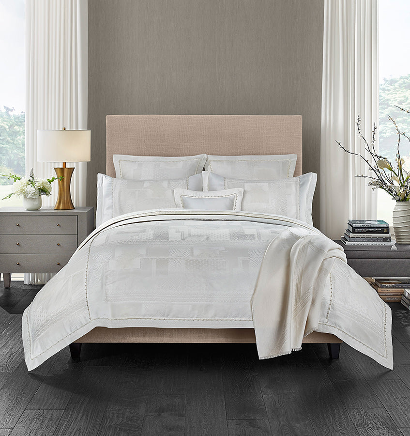 Sferra Regina white jacquard bedding set styled on a bed with ivory throw.