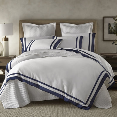 Sferra Savoy white cotton duvet with navy triple-stripe border on styled bed.