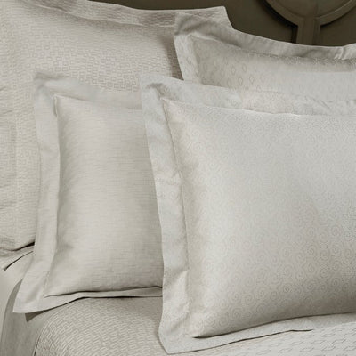 Sferra Scotland ivory jacquard pillow shams and bedding styled on a bed.
