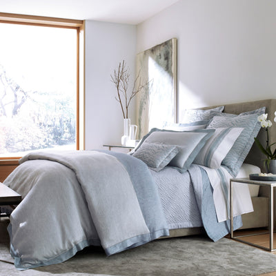 Sferra Seychelles bedding collection in mist blue linen on a styled bed.