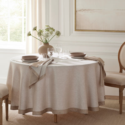 Sferra Seychelles round linen tablecloth in natural on a set dining table.