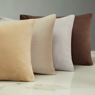 Velveteen cushions in champagne, ivory, dove, and chocolate on marble surface.