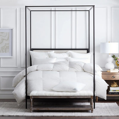 Vienna down collection in white on black iron canopy bed in styled bedroom.