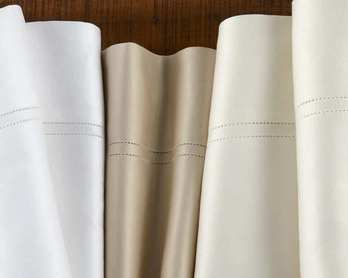 Peacock Alley's 100% cotton white sateen Virtuoso sheet collection stacked neatly