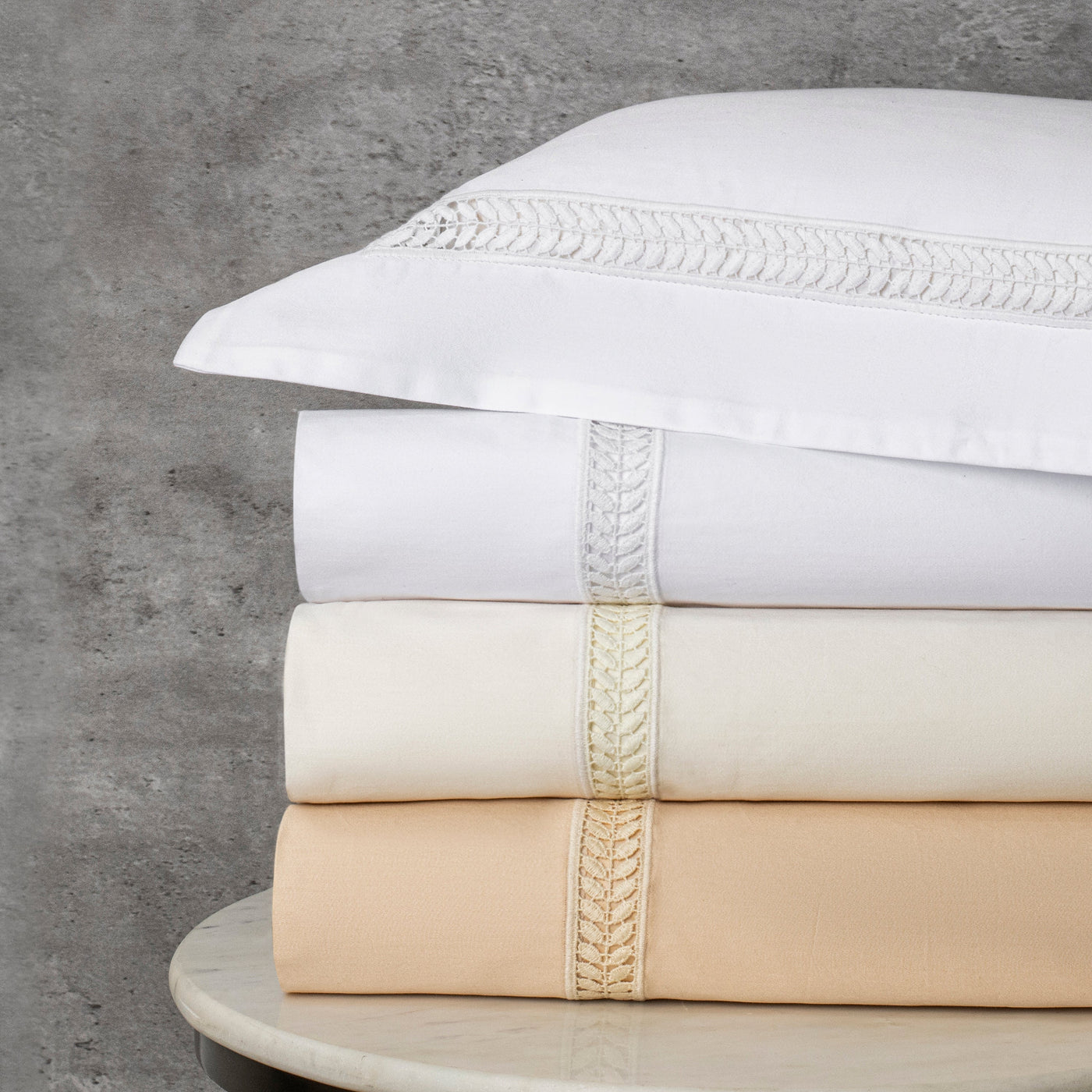 Sferra Wreath folded sheet sets in white, ivory, and champagne with embroidered trim.