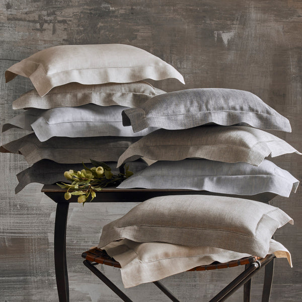 Zebra linen pillowcases stacked in neutral tones on a rustic table and chair.