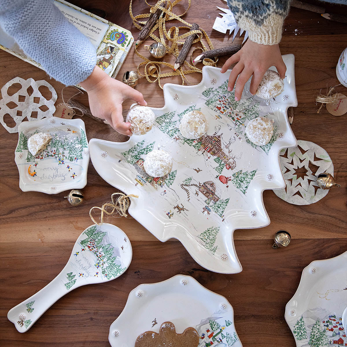 Hands reaching for treats on a North Pole tree platter at a holiday table