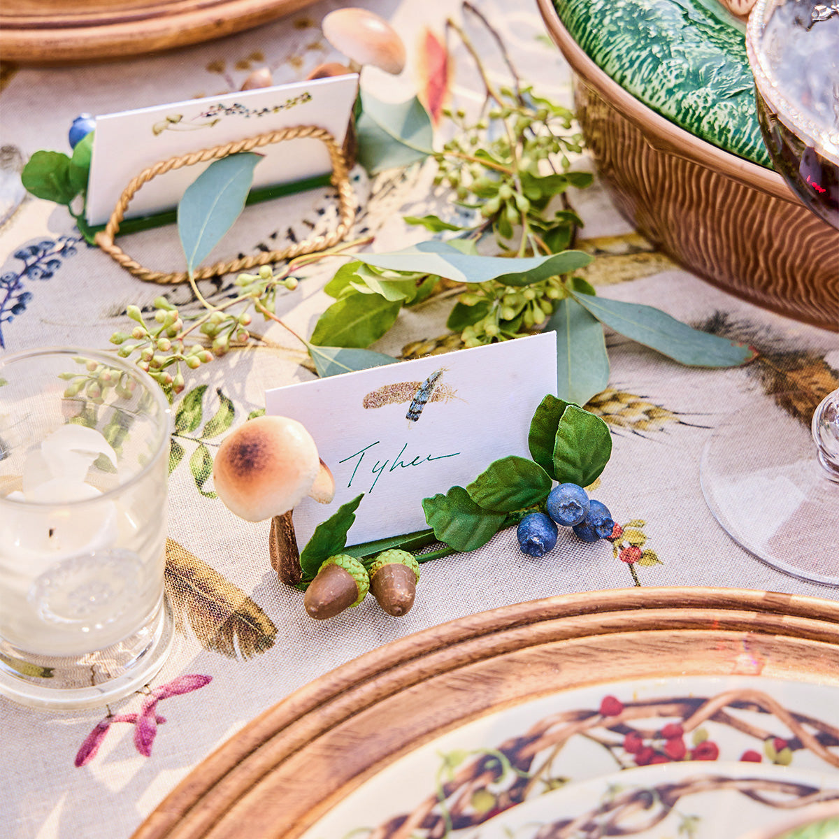 Mushroom place card holder with a name card beside Forest Walk plates and greenery