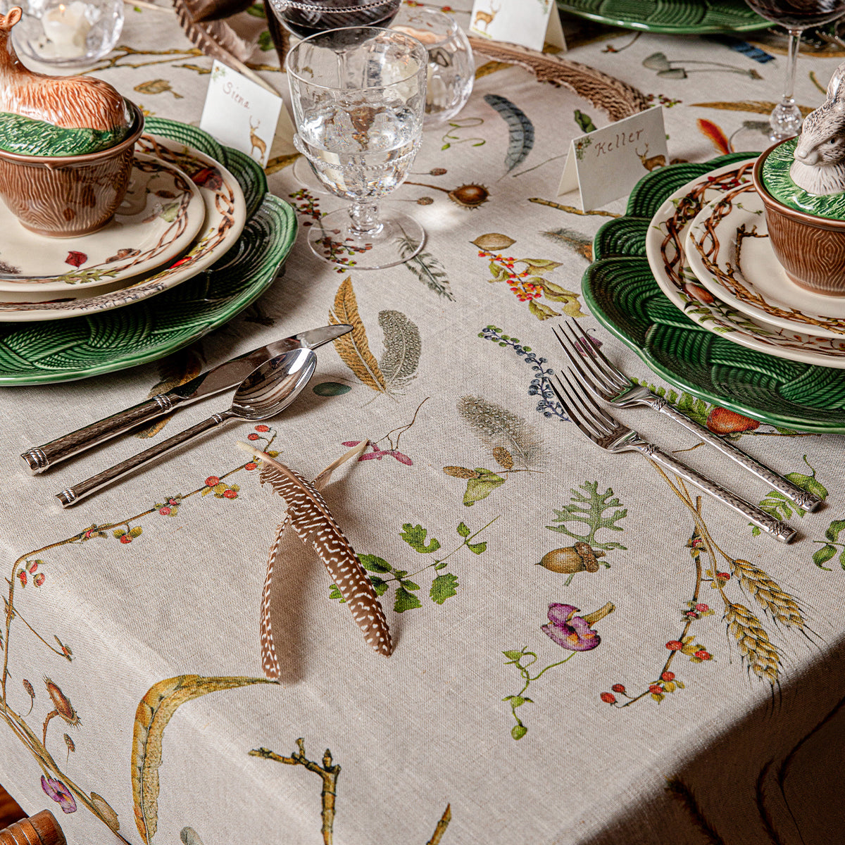 Forest Walk 60 by 120 inch tablecloth with feather and twig print under place settings and glasses