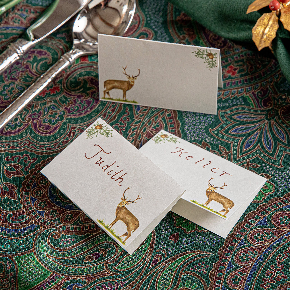 Stag place cards with handwritten names on a paisley tablecloth