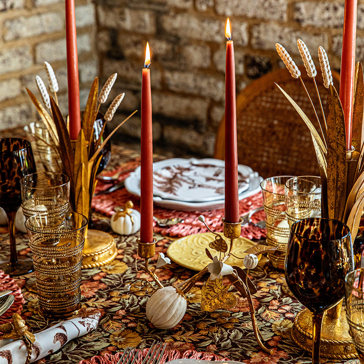 Forest Walk gold pumpkin and vine double candlestick holder with red tapers on a patterned autumn table