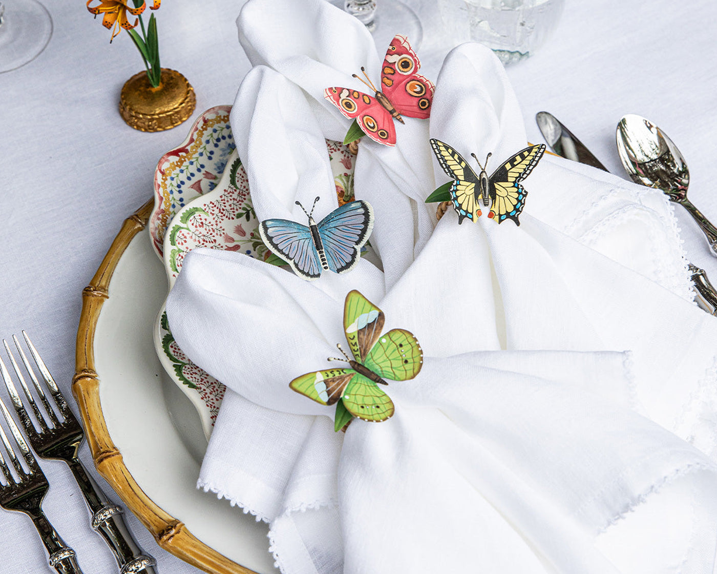Colorful butterfly napkin rings styled on a white linen napkin at a table setting.