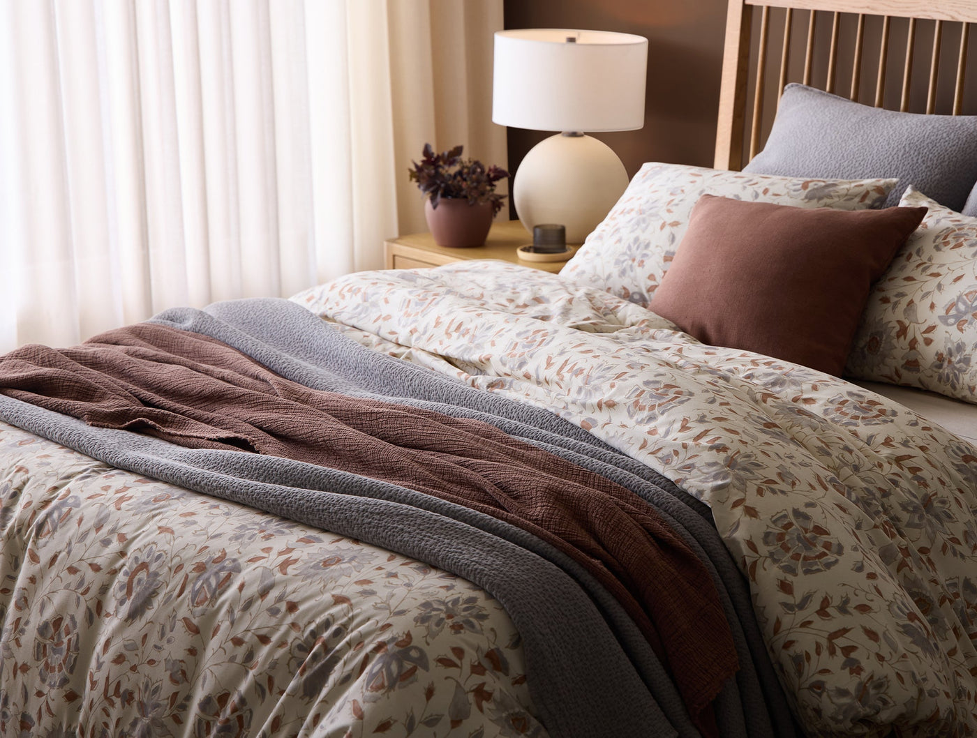 Bed styled with Flora Print duvet, mauve throw, slate blanket, and coordinating pillows.