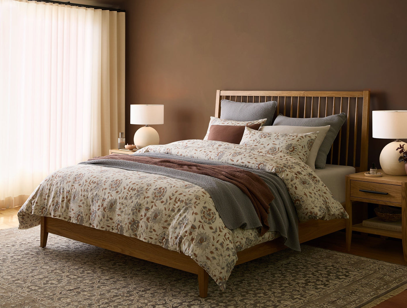 Coyuchi Flora Print duvet cover styled on a bed with dusty blue and terracotta accent pillows.