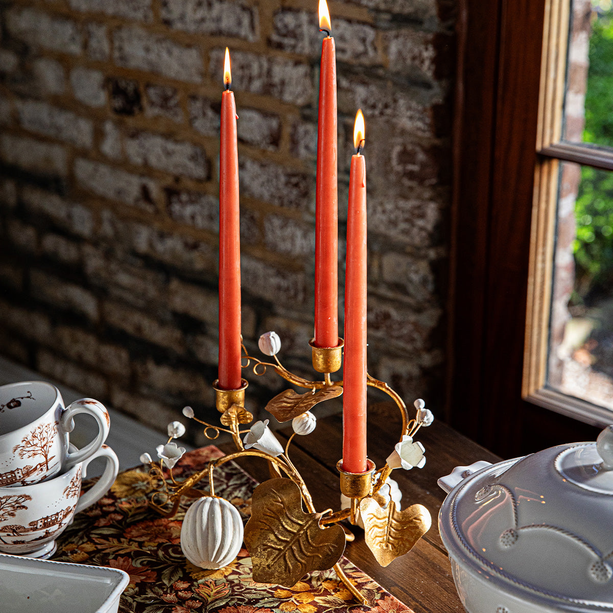 Forest Walk gold pumpkin and vine triple candlestick holder with red tapers on a table set with dishes