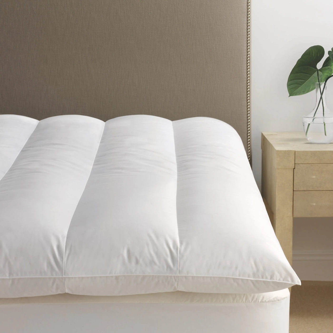 Scandia Home white down featherbed with channel stitching on a bed.