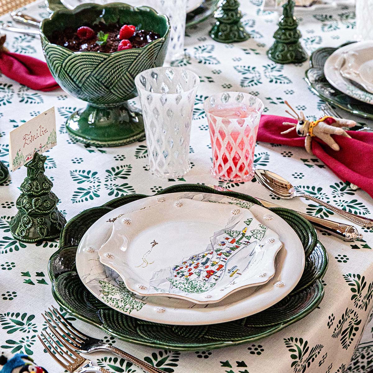 North Pole plates layered on a green scalloped charger with a red napkin on a green and white tablecloth