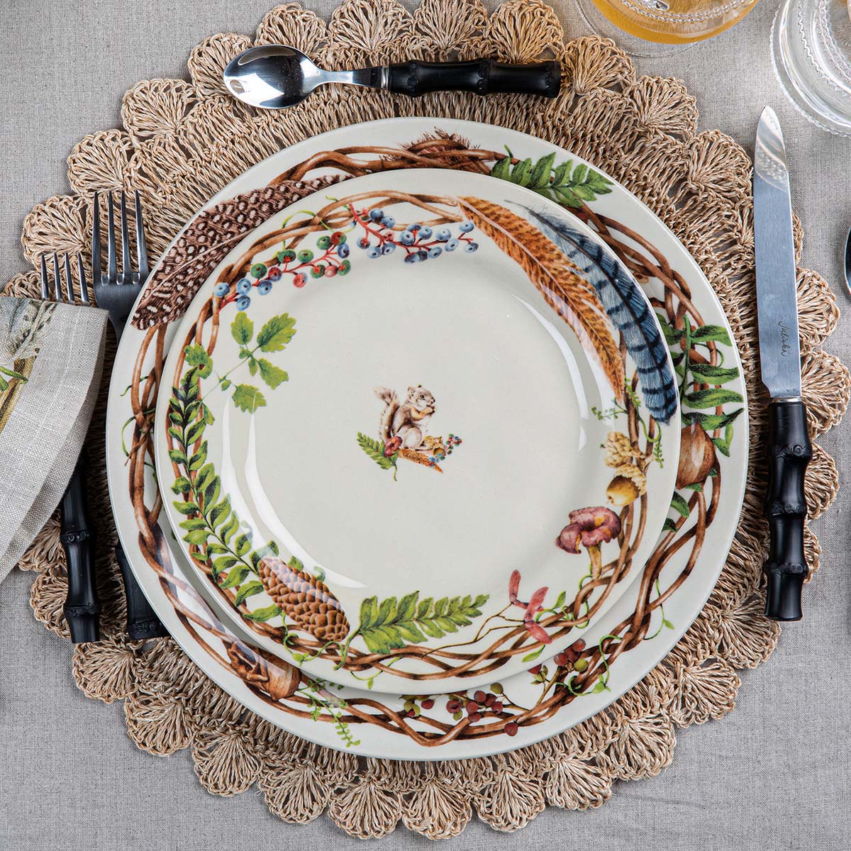 Forest Walk squirrel salad plate stacked on Forest Walk dinnerware over a woven jute placemat