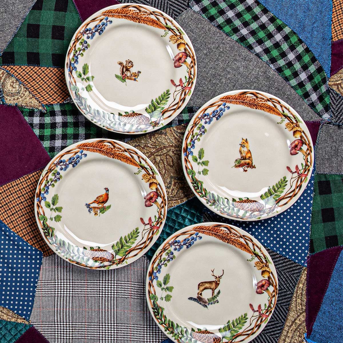 Four Forest Walk animal salad plates arranged on a patchwork plaid wool cloth