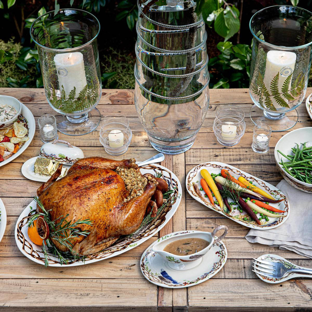 Forest Walk 17 inch platter with a roast turkey on a rustic wooden table with vegetables, gravy boat and candles