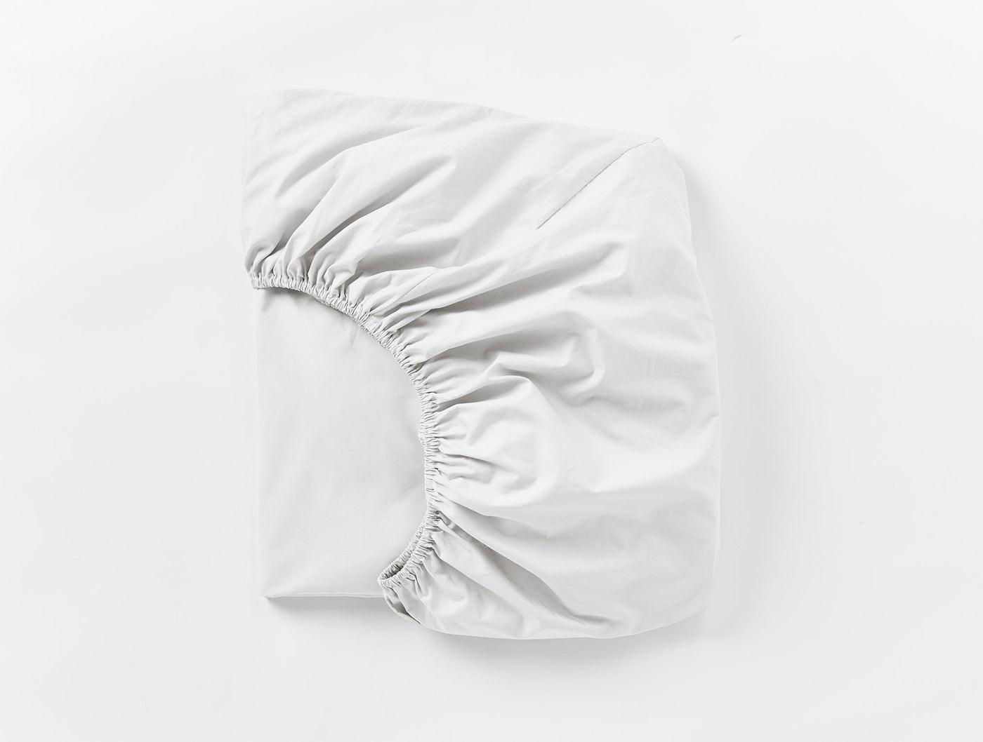 Coyuchi Refined Percale fitted sheet in white, folded to show elasticated corners.