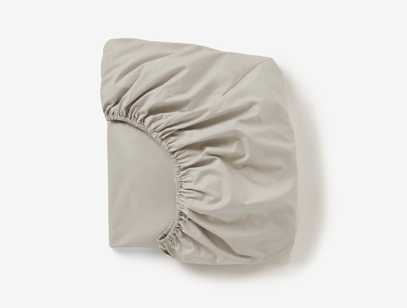 Coyuchi Refined Percale fitted sheet folded to show elasticated corners, stone.