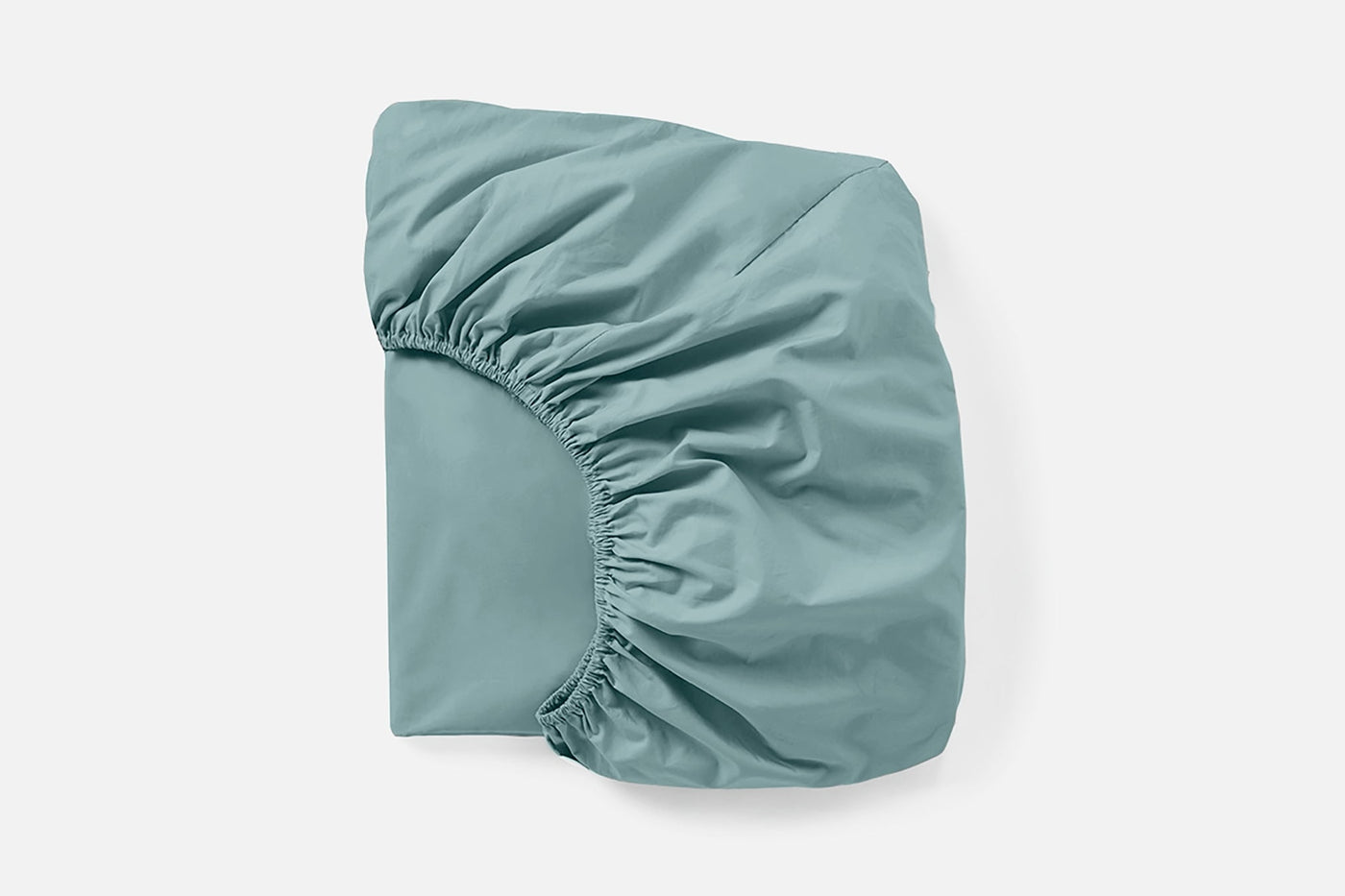 Corner detail of Coyuchi Refined Percale fitted sheet in muted teal, showing elastic gather.