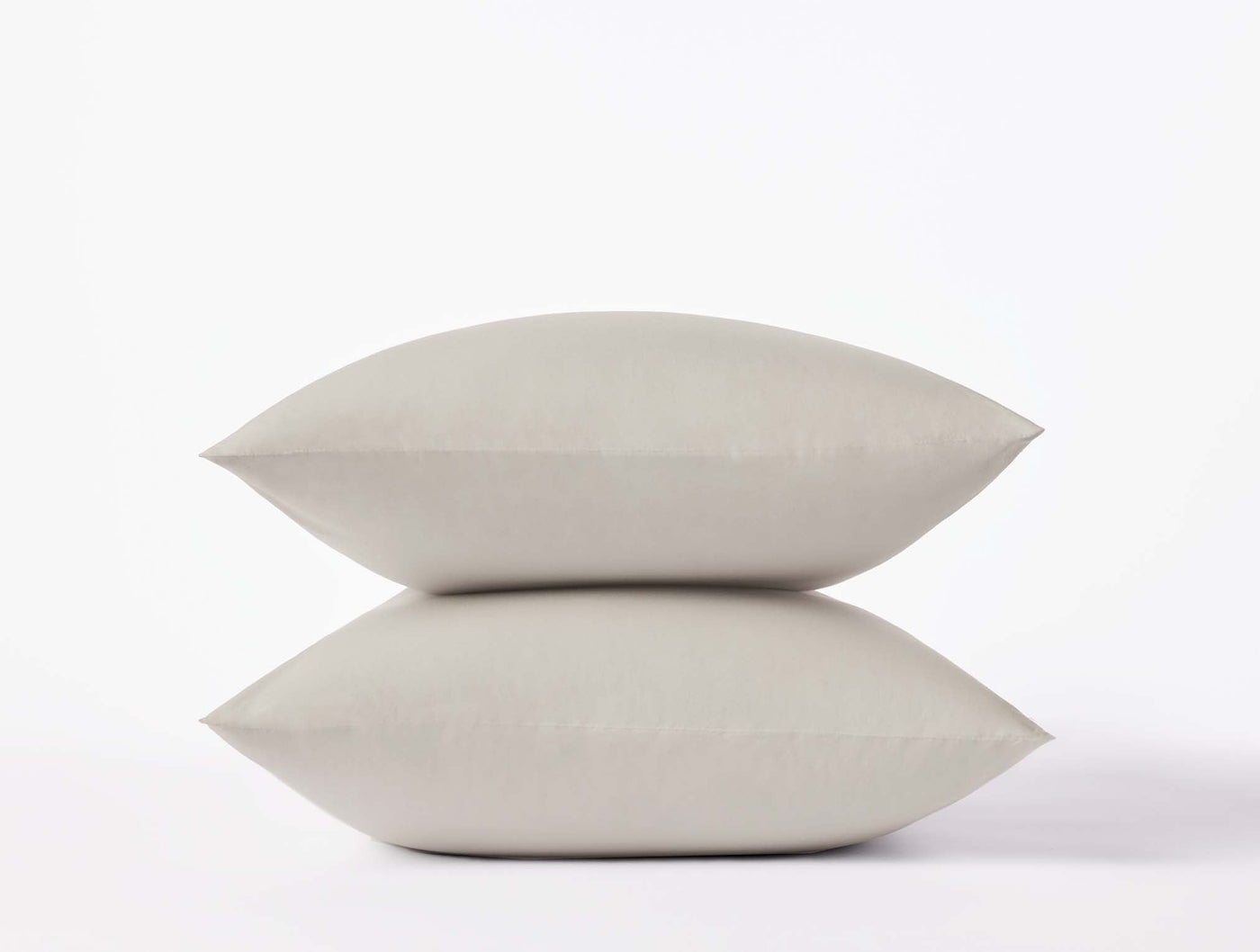 Two stacked Coyuchi Refined Percale pillowcases in stone, smooth matte finish against white background.