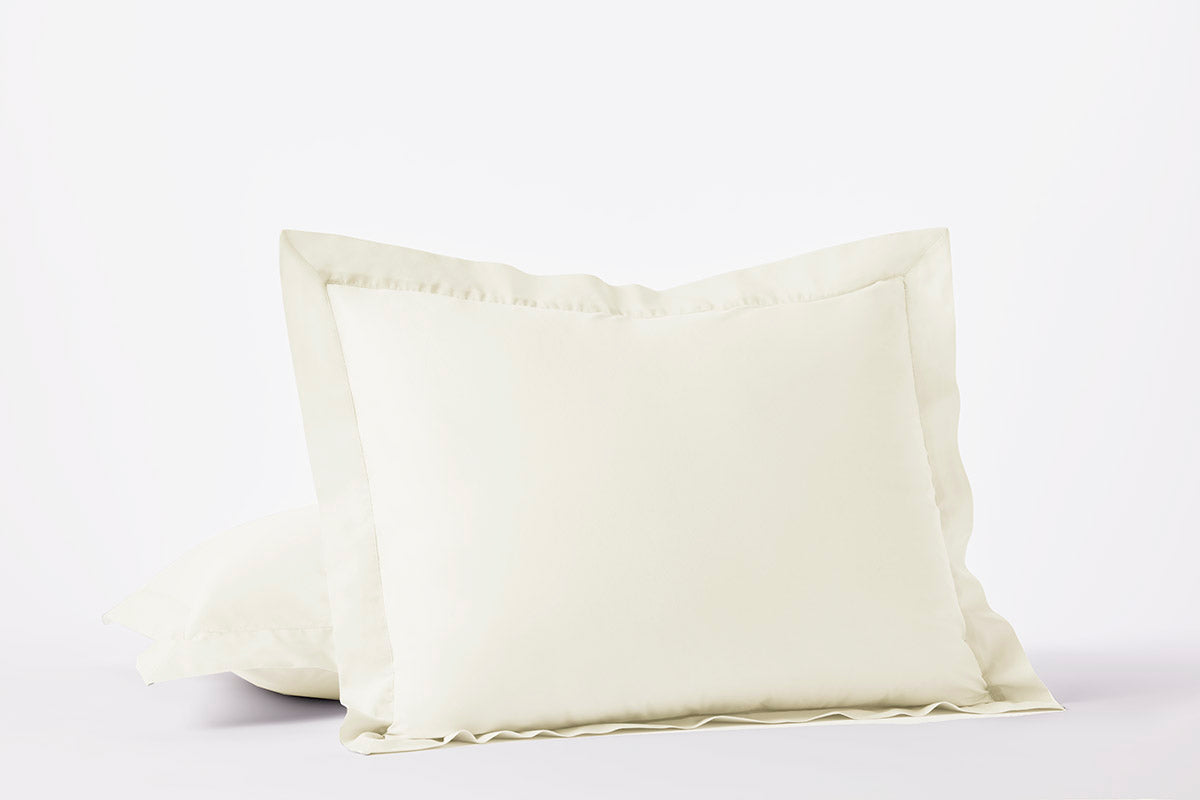 Ivory percale pillow shams with flange trim, stacked pair on white background.