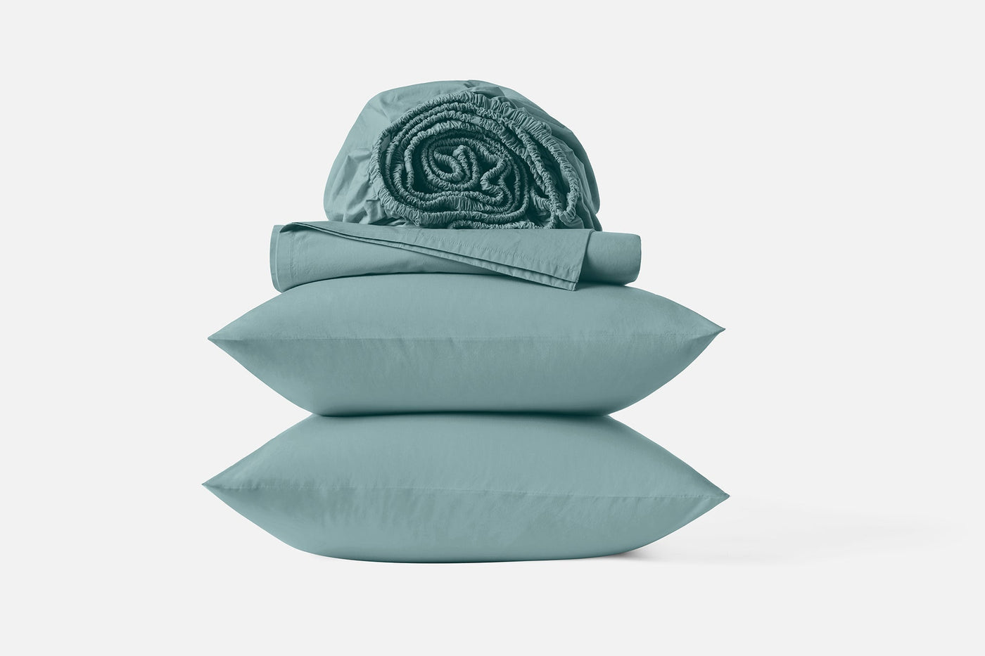 Close-up of stacked Coyuchi Refined Percale pillowcases and rolled sheets in sage green.