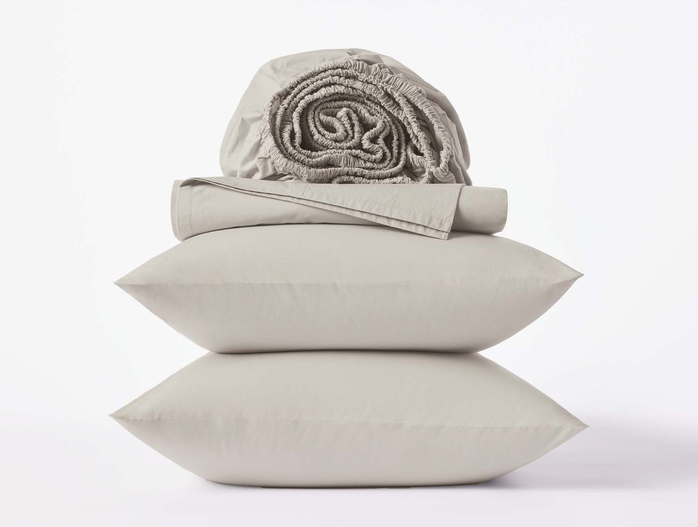 Stacked pillowcases with folded flat sheet and rolled fitted sheet in warm grey percale.