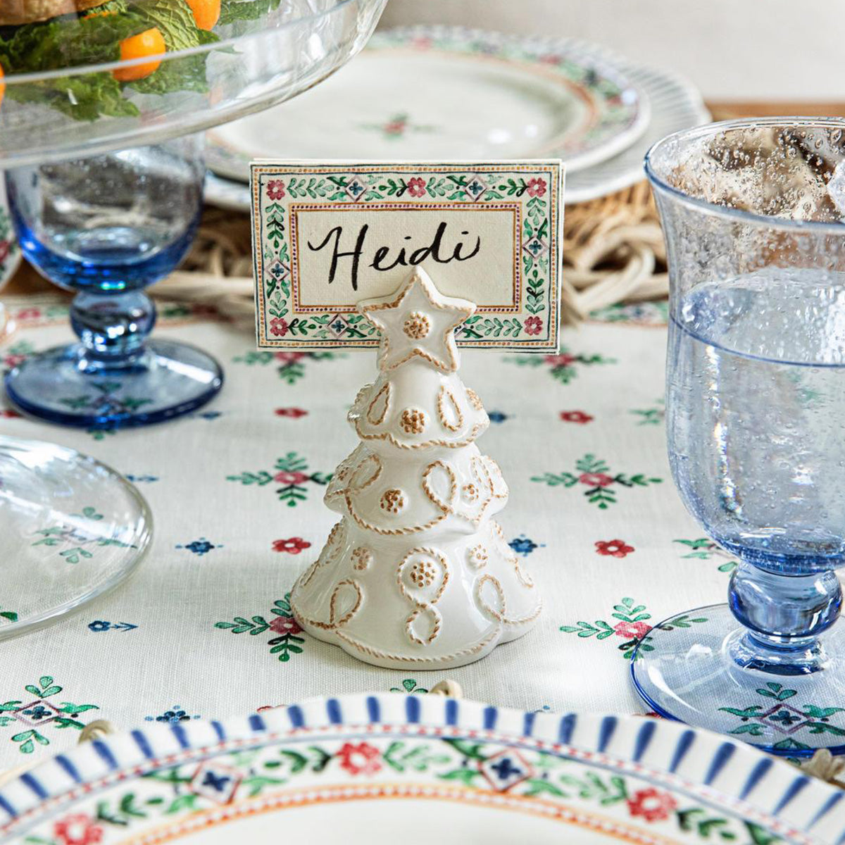 Whitewash tree place card holder with a handwritten card on a table with blue glassware