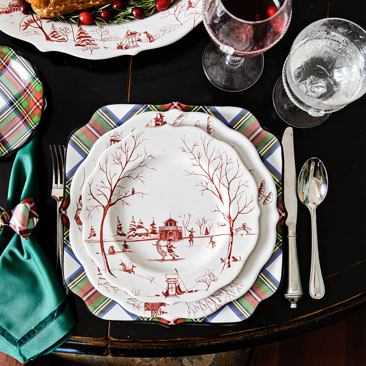 Ruby Winter Frolic salad plate on a plaid charger with a green napkin and silverware