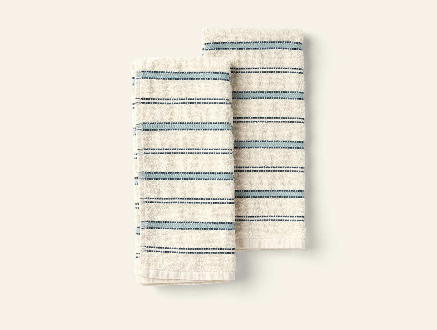 Two folded Coyuchi Acacia hand towels in ivory with blue multi-stripe pattern.
