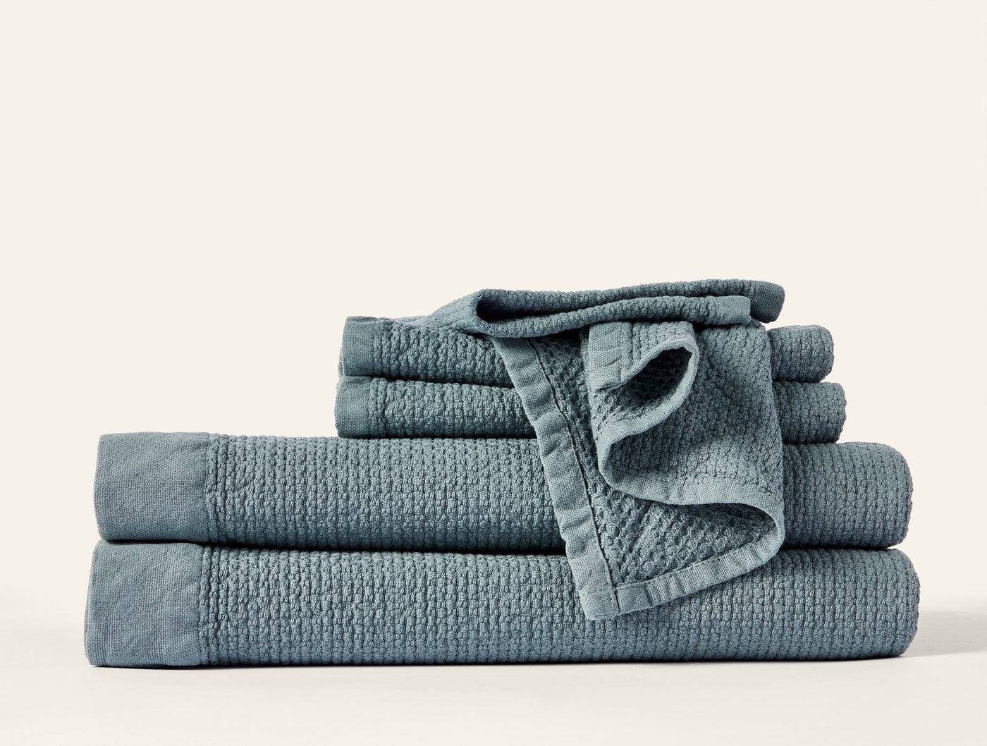 Slate blue textured towel set stacked, showing waffle weave and hem detail.