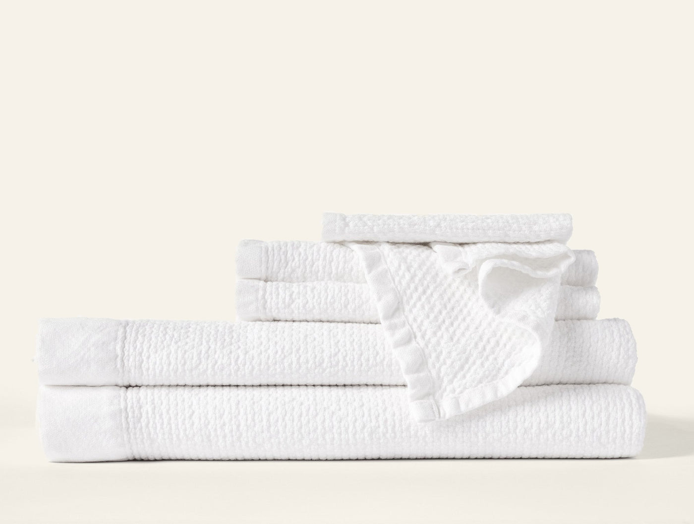 Coyuchi Adriatic white bath towel set stacked, showing textured weave and ruffled trim detail.