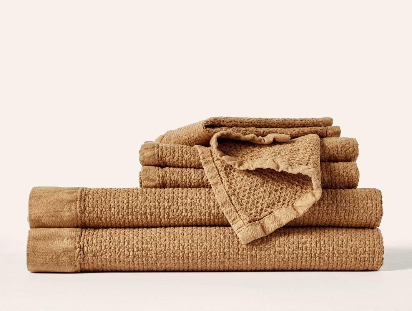 Close-up of stacked caramel waffle-textured towels with ruffled trim detail.
