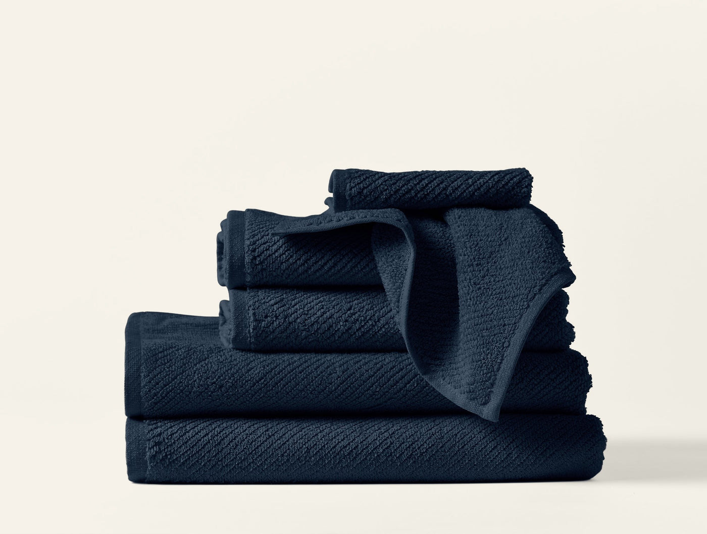 Navy blue Coyuchi Air Weight towels stacked, showing textured weave detail.