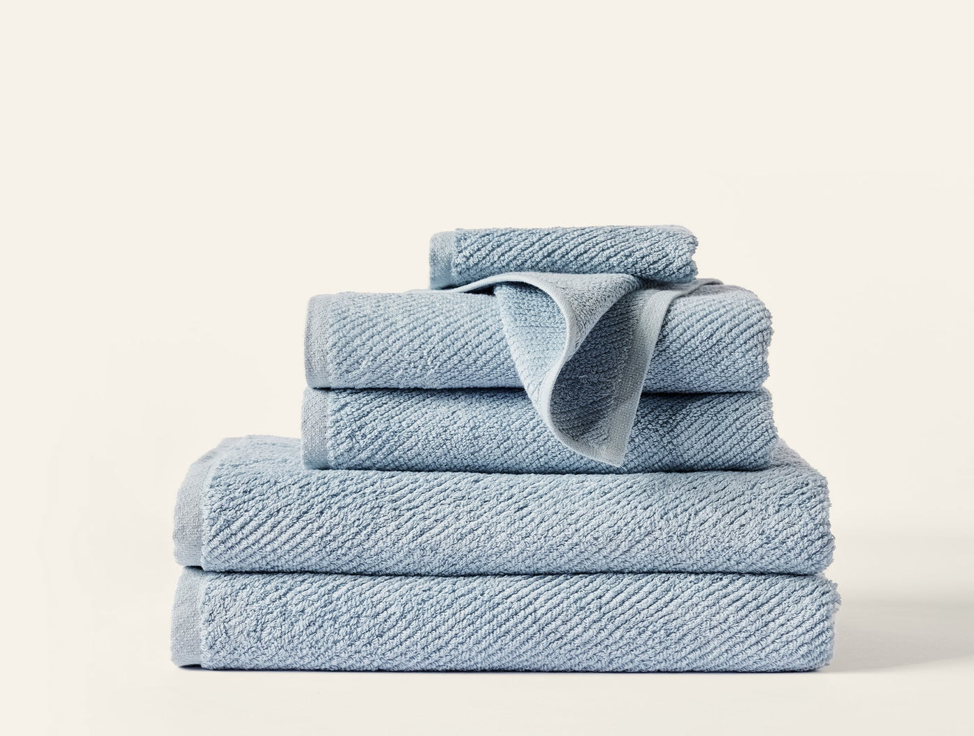 Close-up of stacked Coyuchi Air Weight towels in chambray blue showing ribbed cotton texture.