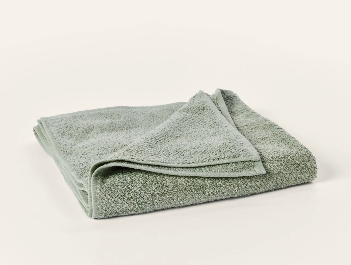 Folded sage green terry guest towel with visible looped texture and corner detail.