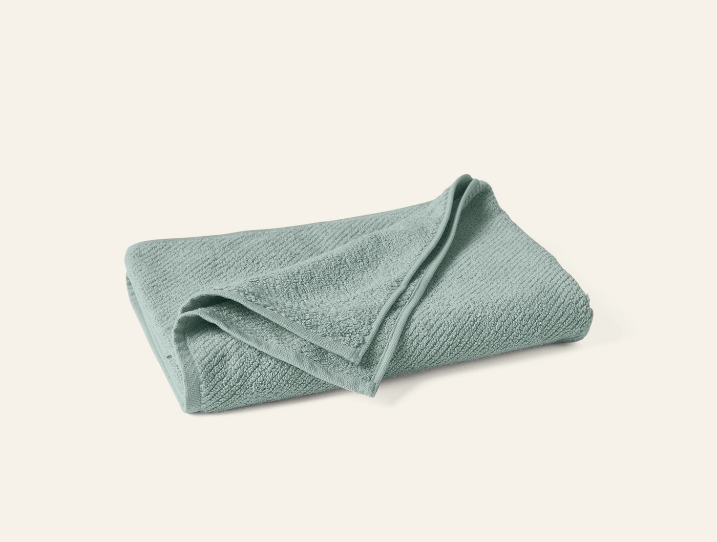 Coyuchi Air Weight guest towel folded, sage green with subtle ribbed texture.
