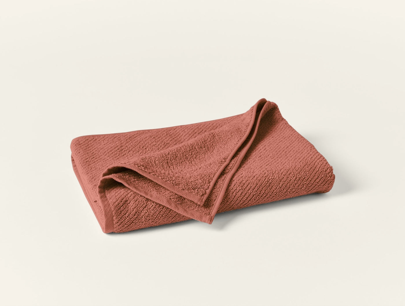 Coyuchi Air Weight guest towel in terracotta, folded to show textured waffle weave.