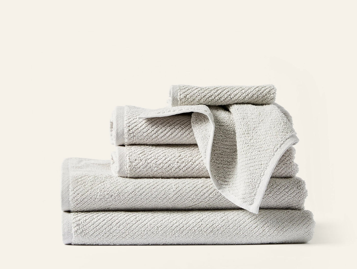 Stacked Coyuchi Air Weight towel set in ivory with ribbed texture, one draped open.