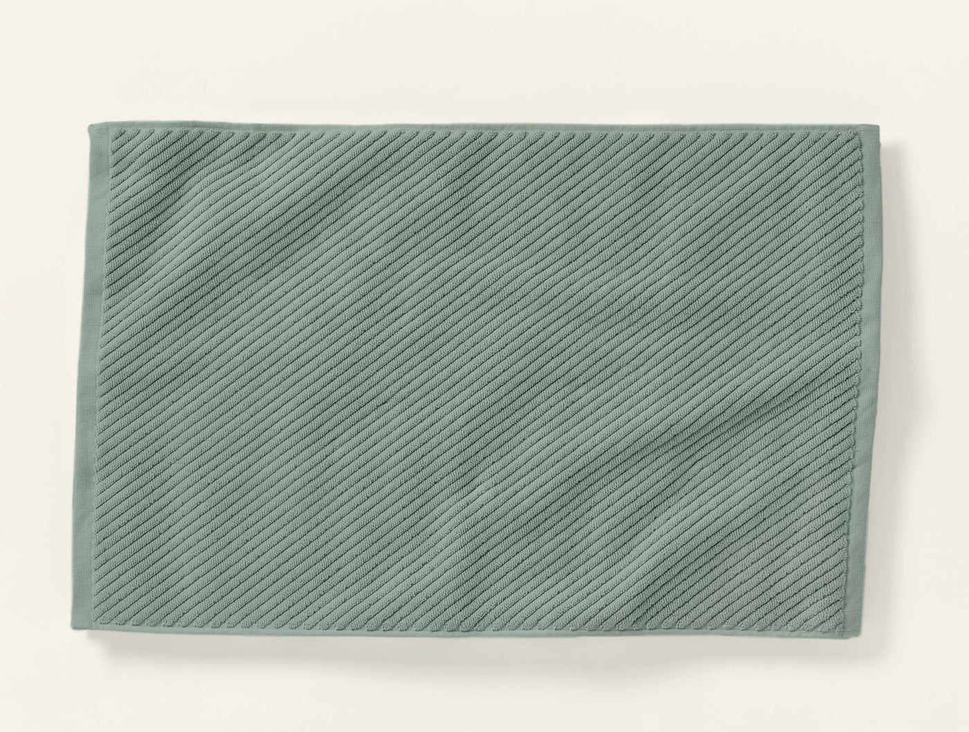 Sage green Coyuchi Air Weight bath rug showing diagonal ribbed twill weave texture, flat lay.